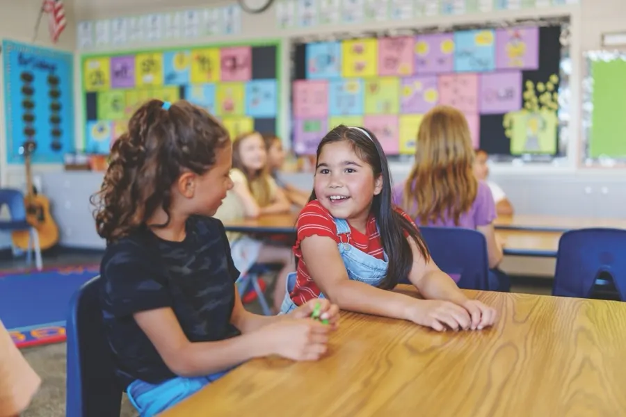 Two students chatting at their classroom desk